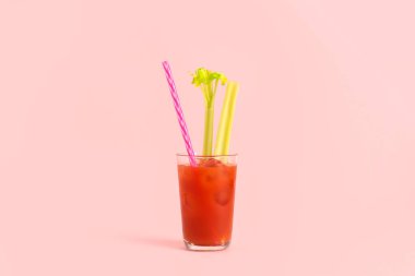 Pembe arka planda kerevizli bir bardak Bloody Mary.