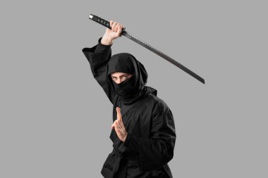 Gri arka planda kılıcı olan erkek ninja.