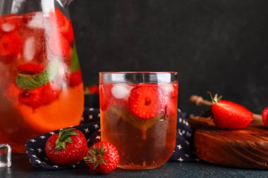 Siyah arka planda çilekli bir bardak erimiş su.