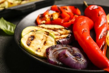 Siyah arka planda lezzetli ızgara sebzeli tabak.