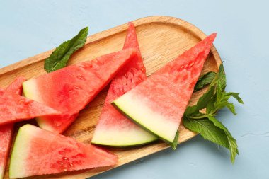 Mavi zemin üzerinde taze karpuz ve nane parçacıkları olan tahta.