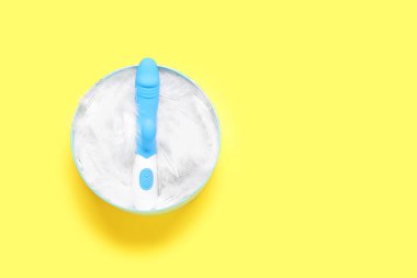 Sarı arka planda tüyleri ve vibratörü olan hediye kutusu.