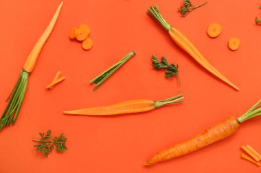 Turuncu arka planda taze havuç ve dilimler.