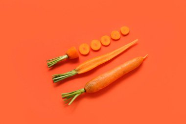 Turuncu arka planda taze havuç ve dilimler.