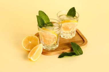 Arkaplanda soğuk mojito, limon ve nane içeren ahşap bir tahta.