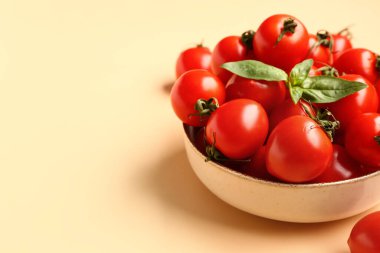 Taze kiraz domatesli kase ve turuncu arka planda fesleğen.