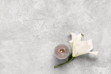 Beyaz zambak çiçeği ve yanan mum gri grunge arka planda