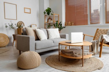 Ahşap sehpada gri kanepe ve dizüstü bilgisayarı olan modern oturma odasının içinde.