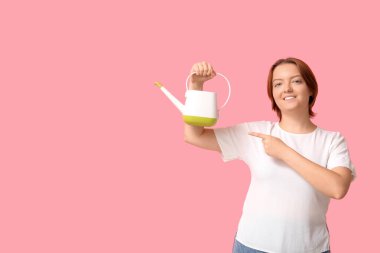 Gülümseyen kadın pembe arka plandaki sulama kutusunu işaret ediyor.