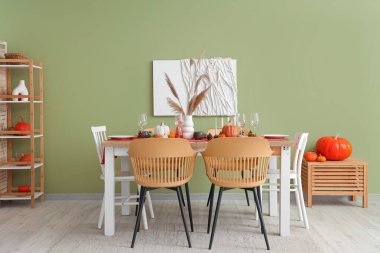 Sonbahar sofrası, balkabakları, kuru yapraklar ve yemek odasında yanan mumlar.