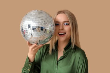 Kahverengi arka planda disko topu olan güzel genç bir kadın.