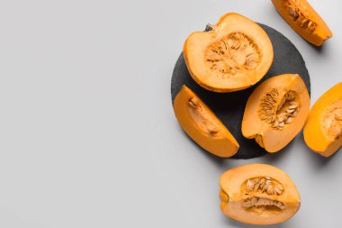 Gri arka planda kesilmiş taze balkabakları olan siyah tahta.