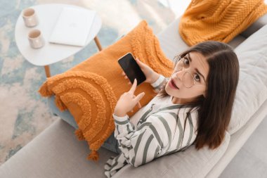 Evinde cep telefonu olan genç bir dedikoducu kadın.