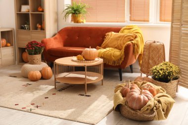 İçinde kahverengi kanepe, ahşap mobilya ve balkabağı olan rahat bir oturma odası.