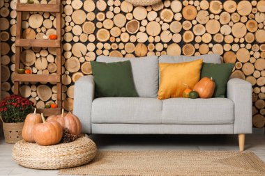 Gri kanepe, hasır puf ve balkabağı olan rahat bir oturma odası.