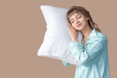 Bej arka planda yastıklı pijamalı güzel bir kadın portresi.