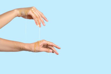 Mavi arka planda, ellerinde bal damlayan bir kadın.