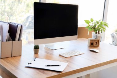 Ofisteki pencerenin yanında dizinleri ve bitkileri olan boş bilgisayar monitörü