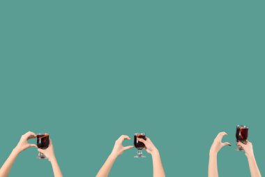 Yeşil arka planda sıcak şarap kadehleriyle kadın elleri.