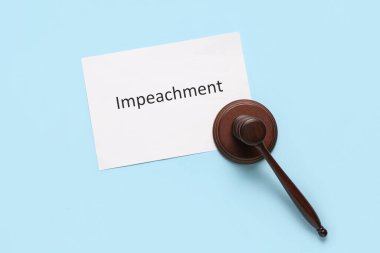 Beyaz arka planda IMPEACHMENT sözcüğüyle Yargıç Tokmak ve kağıt