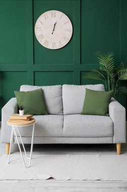 Rahat kanepesi, çiçekleri, masası ve saati olan şık bir oturma odası.