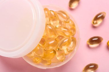 Pembe arka planda balık yağı kapsülleri olan kutu