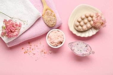 Pembe arka planda vücut fırçası, deniz tuzu ve temiz havlular.