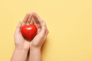 Sarı arka planda kırmızı kalpli kadın elleri