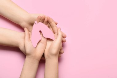 Pembe arka planda kağıt ciğerli kadın ve çocuğun elleri