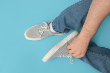 Mavi arka planda gri renkli şık ayakkabılı genç adamın bacakları.