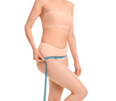 Kalçalarını beyaz arka planda ölçen genç bir kadın. Kilo verme konsepti