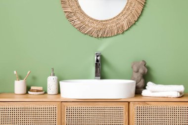 Banyoda yeşil duvarın yanında banyo malzemeleri olan modern lavabo.