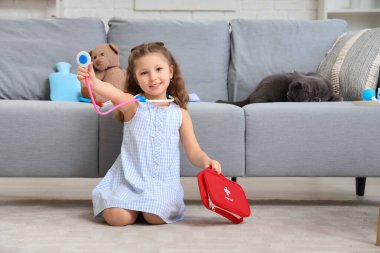 Evinde ilk yardım çantası, steteskop ve İngiliz kedisi olan sevimli küçük bir kız.