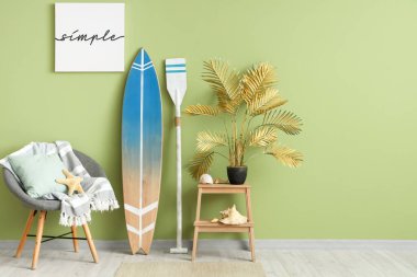 Oturma odasının içinde sörf tahtası, kürek ve koltuk var.