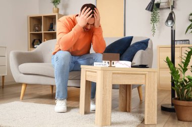 Evde ev modeli olan iflas etmiş bir genç adam.