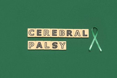 Yeşil arkaplanda CEREBRAL PALSY yazılı saten yeşil kurdele ve plastik harfler
