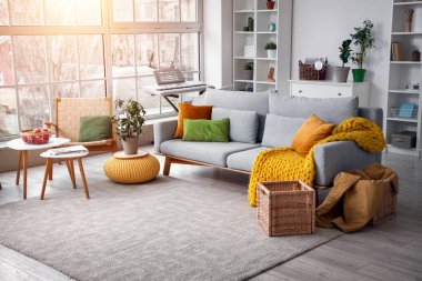 Gri kanepe, koltuk ve raf üniteleriyle oturma odasının içinde.