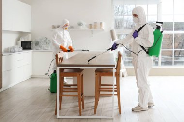 Erkek işçiler mutfaktaki masayı dezenfekte ediyor