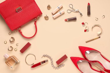 Kırmızı çantadan yapılmış çerçeve, ruj ve bej arka planda güzel mücevherler.