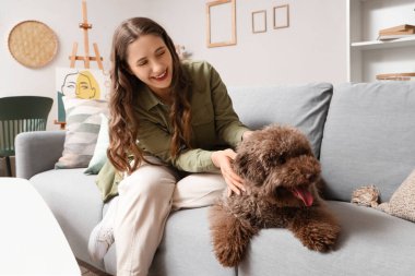 Evdeki kanepede oturan sevimli kanişiyle genç bir kadın.