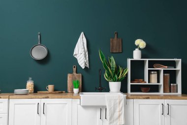 Interior of modern kitchen with white counters, shelves and utensils