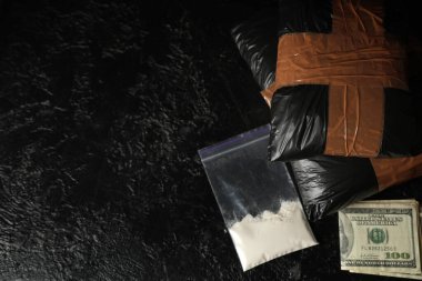 Koyu arkaplan üzerinde para olan uyuşturucu paketleri