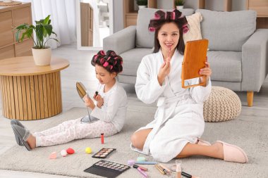 Küçük Asyalı kız ve annesi evde ruj sürüyorlar.