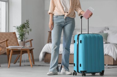 Bavullu kadın, pasaport ve biletler açık otel odasında.