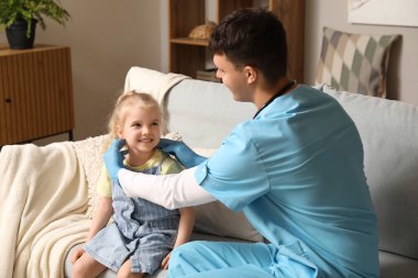 Erkek çocuk doktoru küçük kızı muayene ediyor.