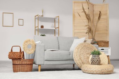 Gri kanepeli, örgülü sepetli ve otlu şık bir oturma odası.