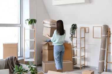Taşındığı gün oturma odasında karton kutuları olan genç bir kadın.
