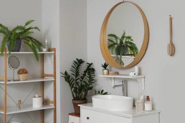 Lavabosu, aynası ve çekmeceleri olan modern bir banyo.