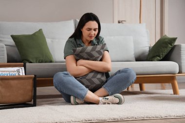 Depresyonda genç bir kadın yastıkla evde oturuyor.