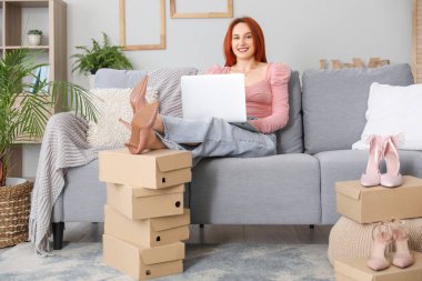 Evde dizüstü bilgisayar kullanan genç bir kadın.